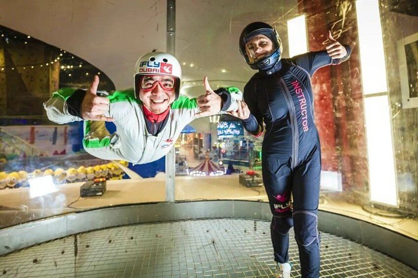 Deux personnes, attachées à un harnais de saut à l’élastique, lèvent le pouce en signe d’approbation. On peut voir en arrière-plan la plateforme de saut et le filet de sécurité. 4