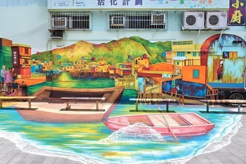 A colorful mural of a village scene with boats on water, buildings, and a person on a bicycle. 2