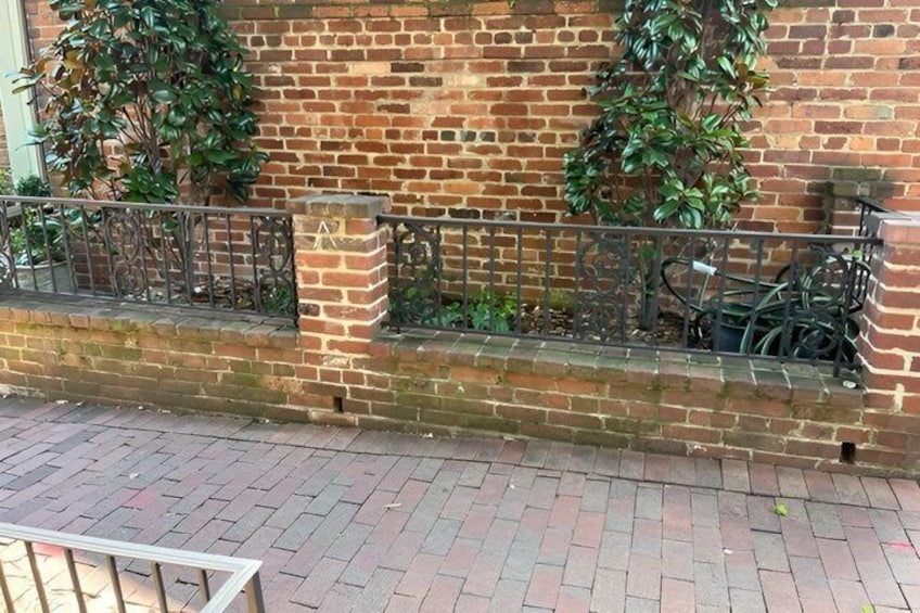 Un muro de ladrillo con una cerca de metal y plantas en macetas. 4