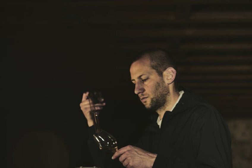 A person holding a bottle, possibly a wine bottle, in a dimly lit environment. 2