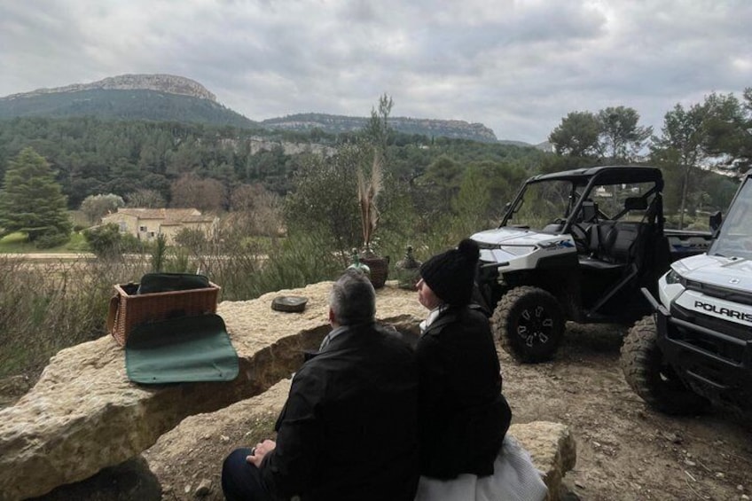 Two people sitting on a rock with a vehicle in the background. 4