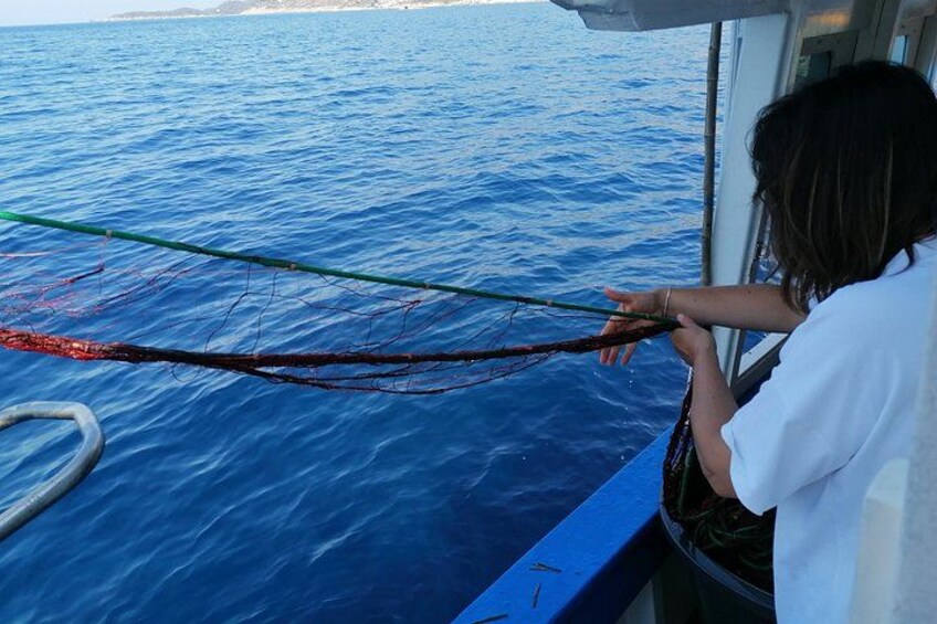 A person handling a fishing net on a boat. 3