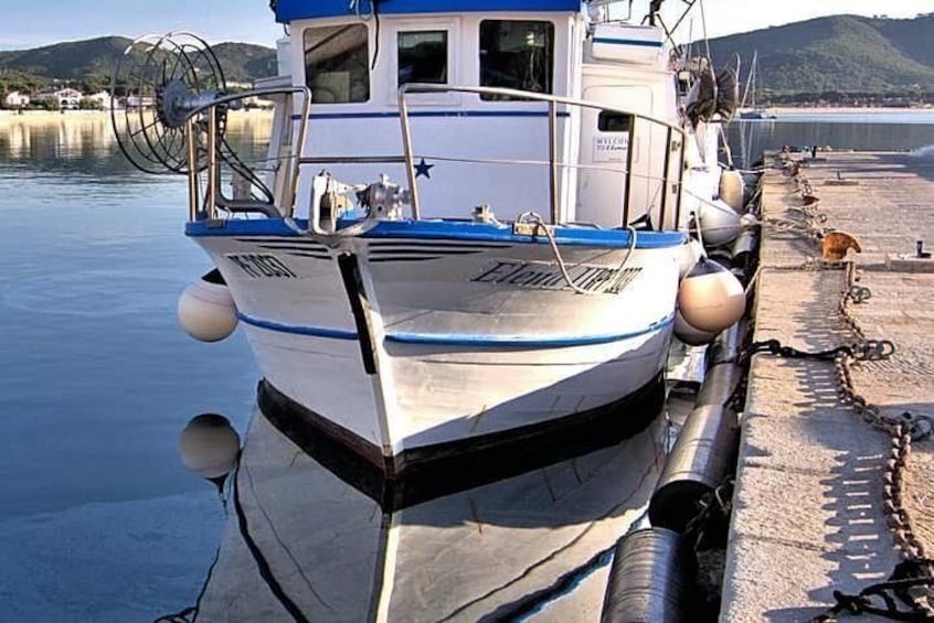 Ein Boot liegt an einem Steg, im Hintergrund ruhiges Wasser und Hügel. 3