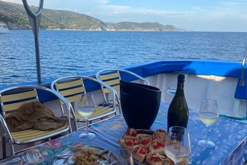 A boat table with food, wine glasses, and a bottle. 5