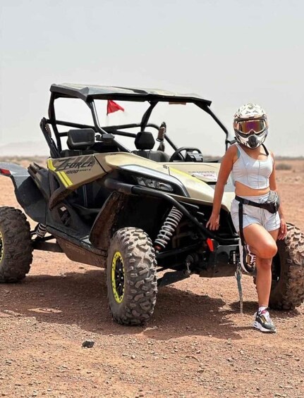 A person standing next to a yellow and black off-road vehicle in a desert. 1
