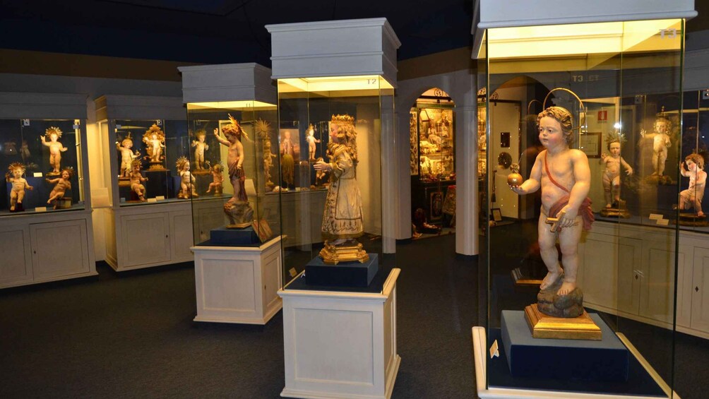 A museum interior with glass display cases containing various statues and artifacts. 1