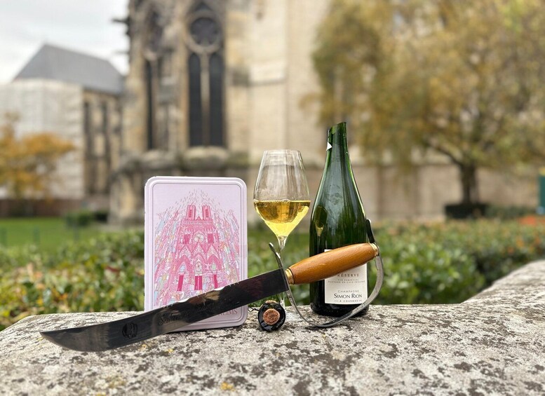 A bottle of champagne, a glass, and a deck of cards on a stone surface with a church in the background. 3