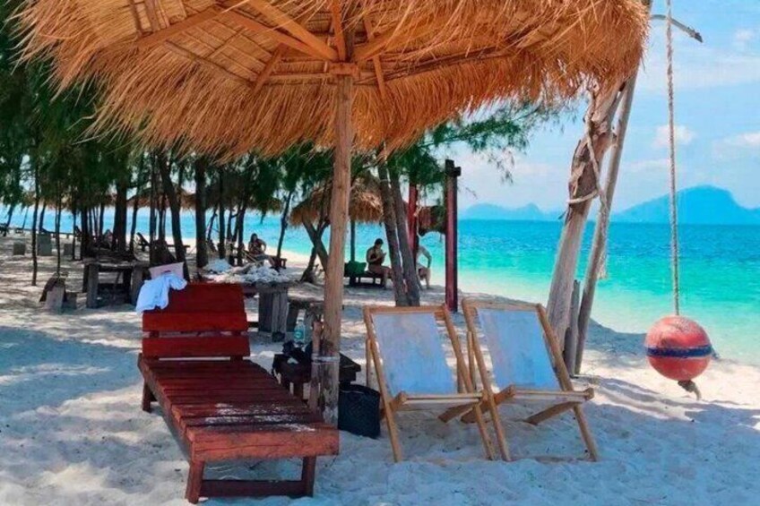 Una spiaggia con lettini di legno, un ombrellone di paglia e un'amaca. 2