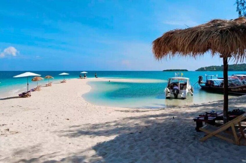 Una spiaggia con acque turchesi cristalline, una barca e ombrelloni. 3