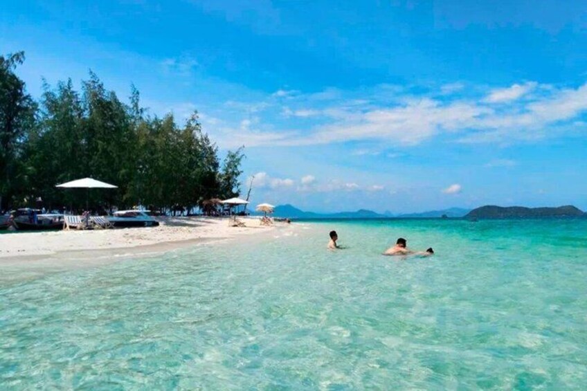Una spiaggia con acqua cristallina turchese, persone che nuotano e una fila di capanne sulla spiaggia. 5