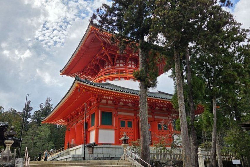 A traditional Japanese temple with a red torii gate, surrounded by trees. 1