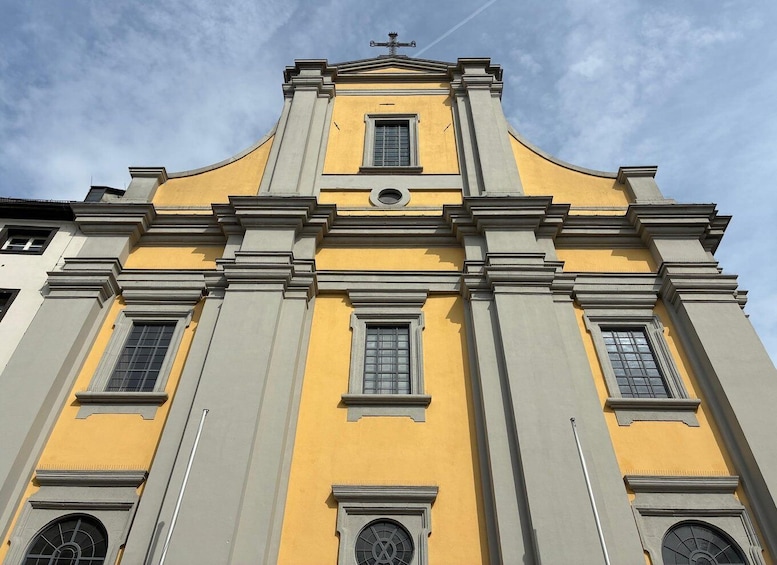 A yellow church with a cross on top, large windows, and a bell tower. 5