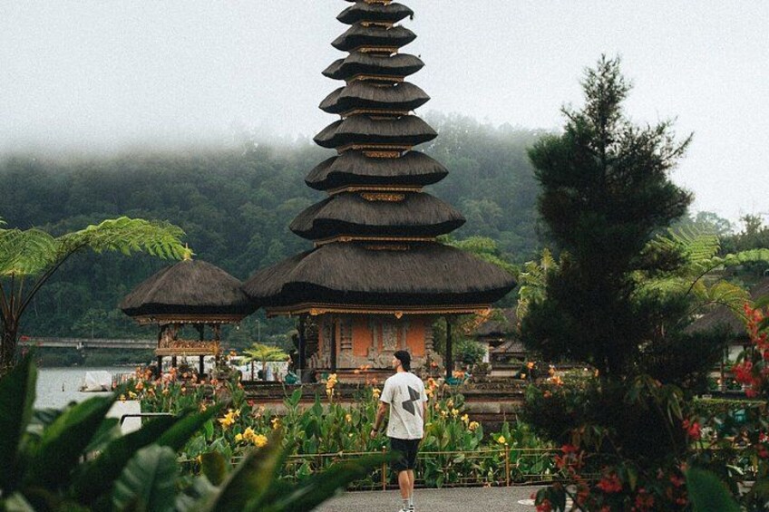 Una pagoda tradicional de varios niveles, abundante vegetación y una persona caminando hacia ella. 1
