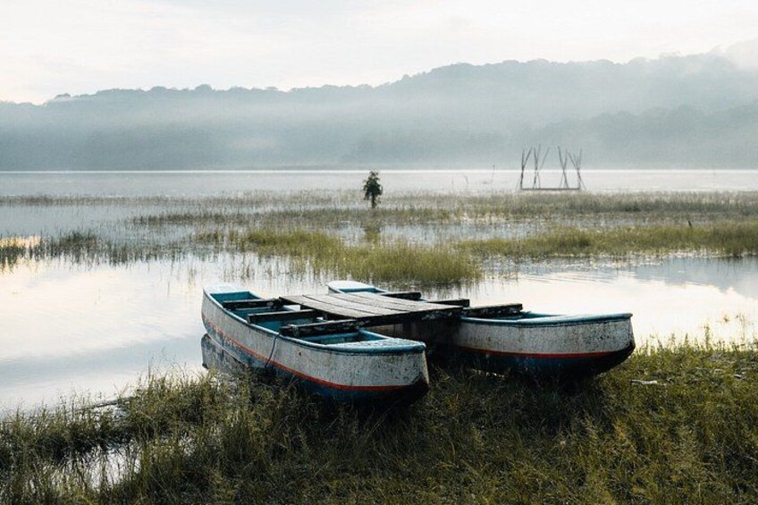 Dos barcos en un lago tranquilo, con un fondo brumoso y colinas al lejano. 5