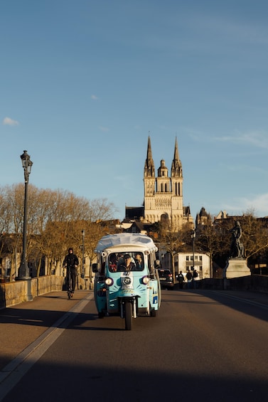 A vintage blue tram on a bridge with a cathedral in the background. 1
