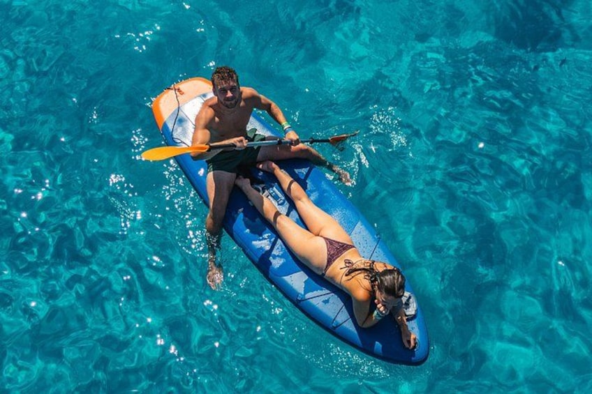A person paddling a blue inflatable raft in clear blue water. 3