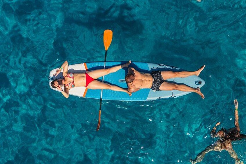 Two people floating on a paddleboard in a clear blue pool. 2