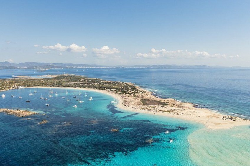 A coastal landscape with clear turquoise waters, a sandy beach, and boats anchored near the shore. 2