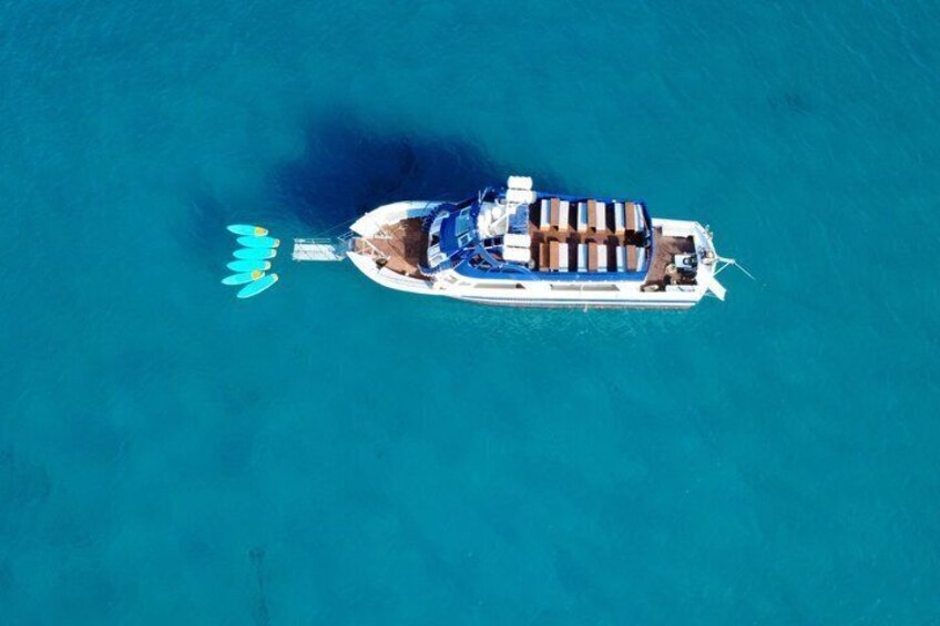 A boat with a blue and white hull, a cabin, and a wake in the water. 1