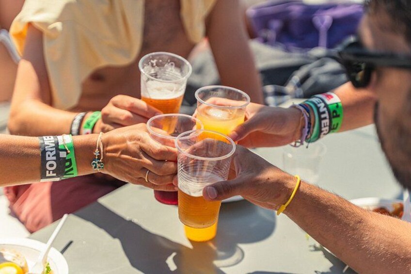 People toasting with plastic cups filled with a yellowish beverage, possibly beer, at an outdoor event. 5
