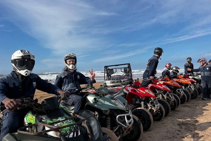 A group of people on ATVs lined up on a beach with a vehicle in the background. 5