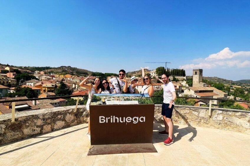 A group of people standing on a rooftop with a sign reading 'Brihuega.' 2