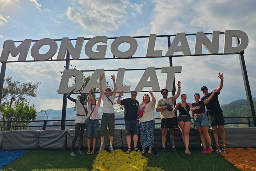 Un grupo de personas posando frente a un letrero que dice 'MONGOLAND DALAT'. 2