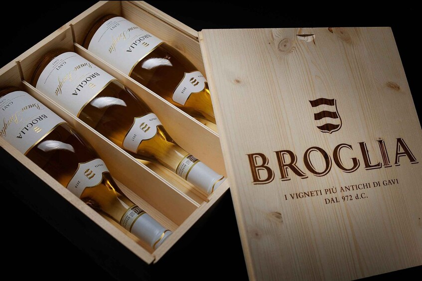 A wooden box with wine bottles labeled 'BROGLIA' and 'I VIGNETI PIÙ ANTICI DI GAVI DAL 972 d.C.' 5