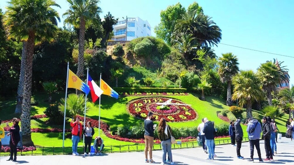 A landscaped garden with a circular floral design, palm trees, and flags. 3