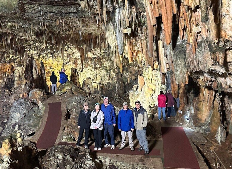 A group of people standing in a cave with stalactites and stalagmites. 2