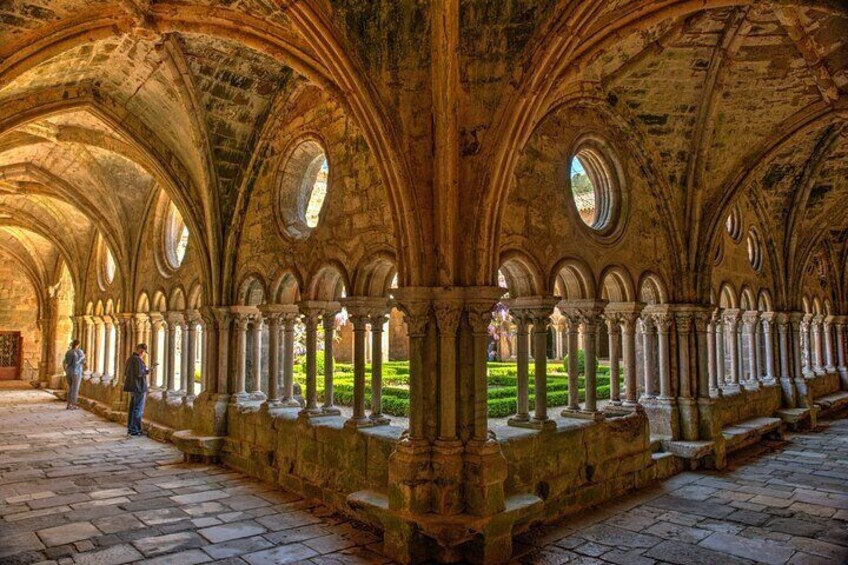 A historic cloister with arched walkways and columns, surrounded by a stone pavement. 1