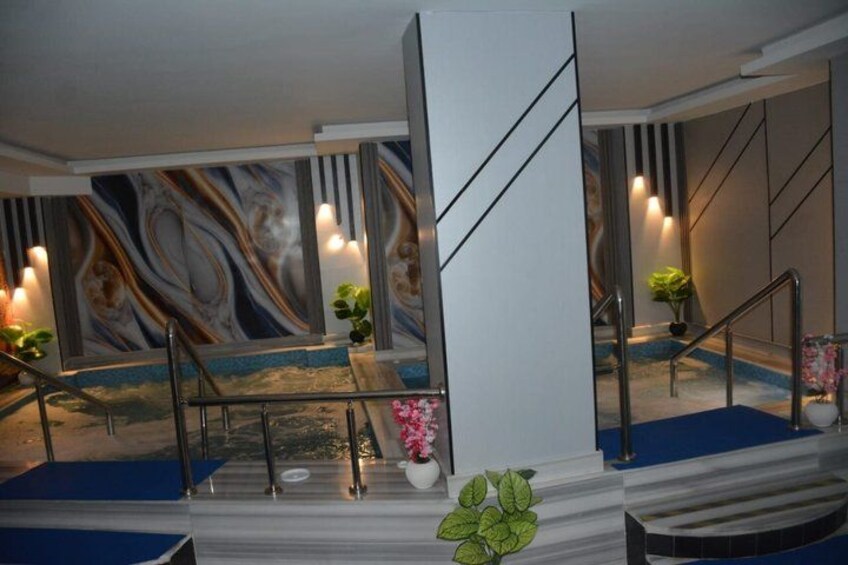 A staircase with blue carpet, metal railings, and a marble wall with a floral pattern. 2