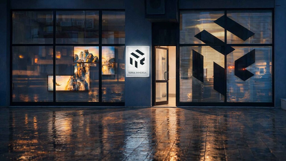 A modern building with large windows displaying artwork, a logo for 'TERRA IMMERSIA,' and a geometric metal facade. 4