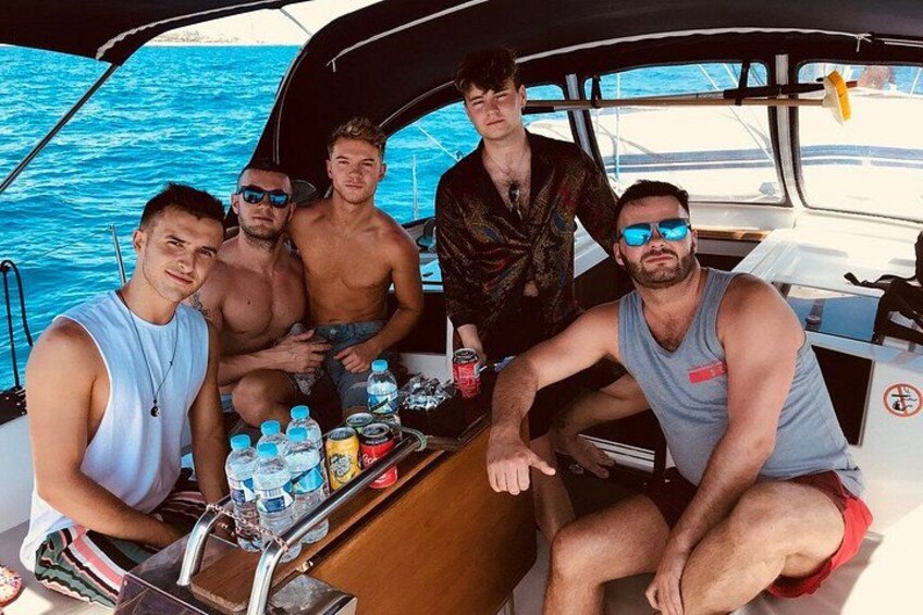 A group of people on a boat with a table of drinks and snacks. 3