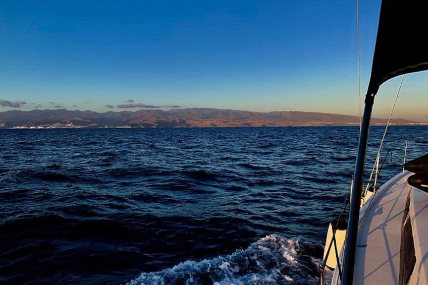 A boat on a body of water with waves, a clear sky, and distant landforms. 4