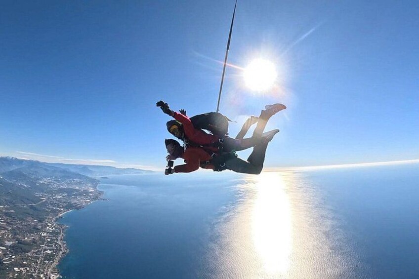 A person skydiving with a parachute over a coastal landscape. 5