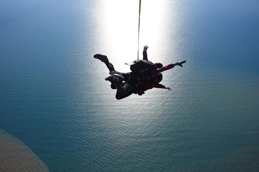A person skydiving with a parachute above a body of water. 3