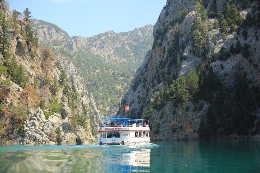 A boat on a calm river surrounded by rocky cliffs and sparse vegetation. 4