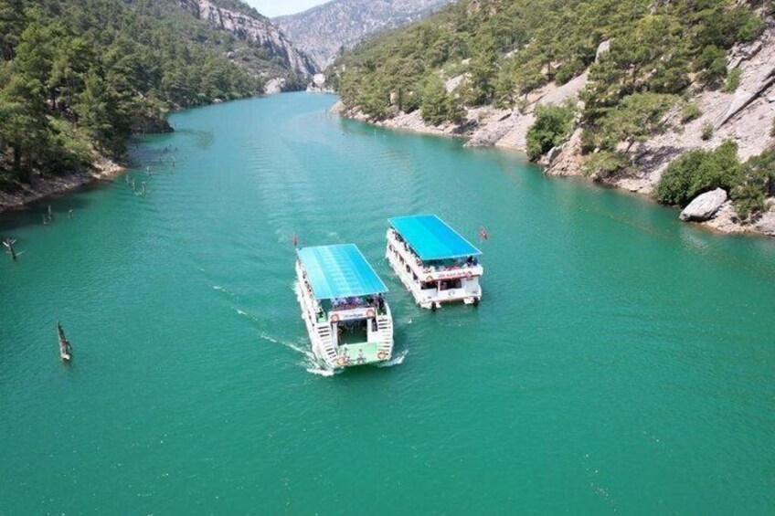 Two boats on a river surrounded by greenery and rocky terrain. 1