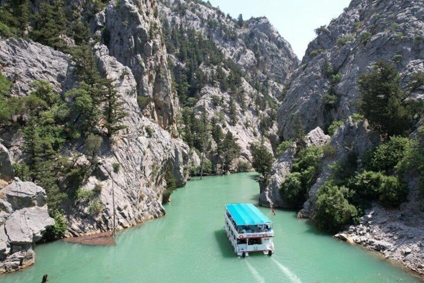 A bus on a narrow river surrounded by rocky cliffs. 5