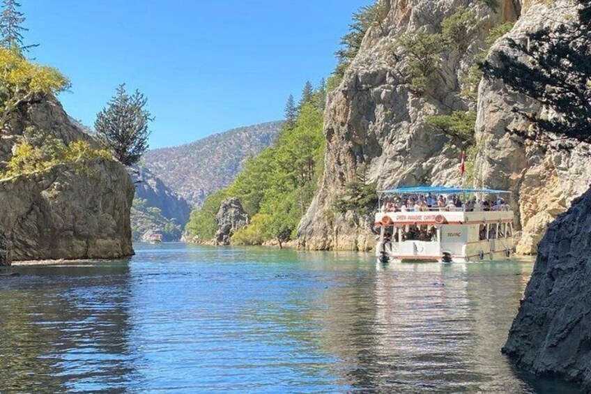 A boat on a river with rocky cliffs and trees. 3
