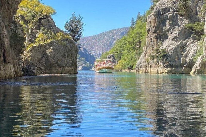 A river with a boat, rocky cliffs, and trees. 2