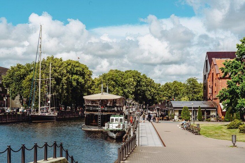 A riverside town with a dock, boats, and a pedestrian walkway. 4