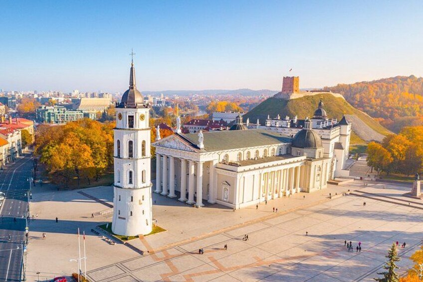 A historic building with a prominent tower, a large dome, and a hilltop fortress in the background. 3