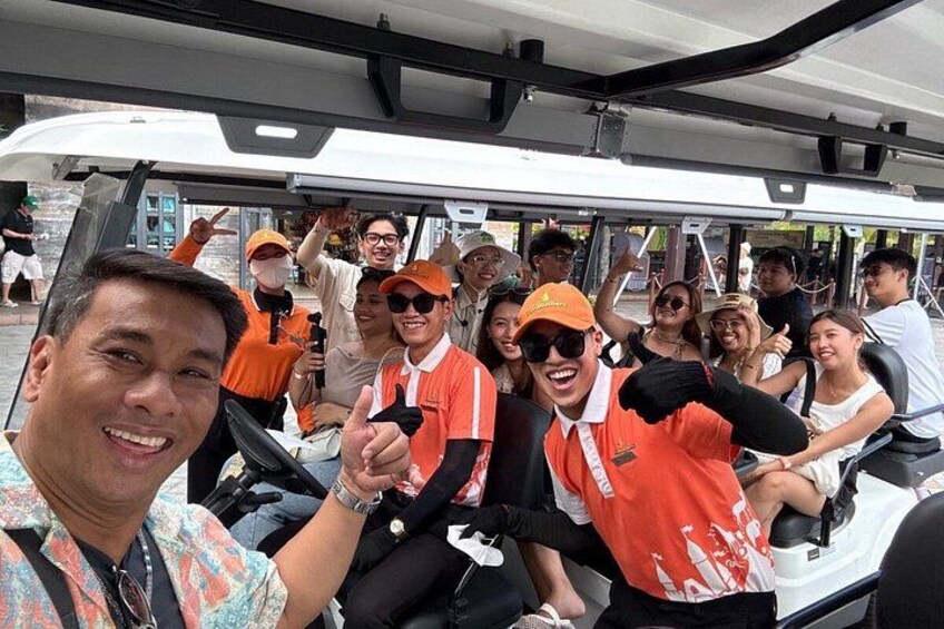 Eine Gruppe von Menschen in orangefarbenen Hemden in einem Bus, einige machen die Daumen hoch. 4