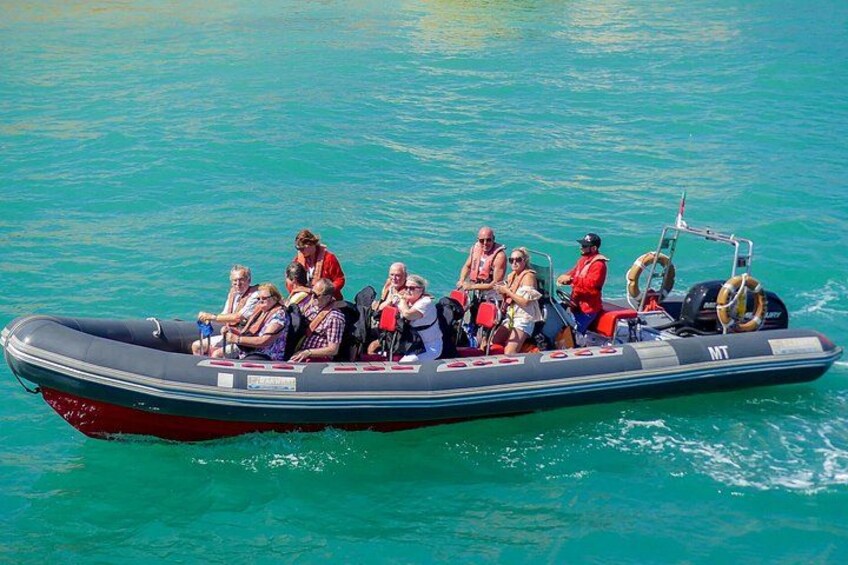 Een opblaasbaar bootje met verschillende mensen erin, drijvend op turquoise water. 2