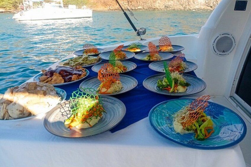 A boat with a table set with plates of food, surrounded by water and a distant shoreline. 3