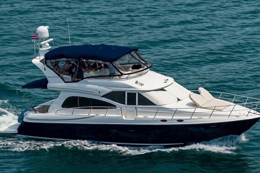 En stor, elegant yacht med ett övre däck som är delvis täckt, vit skrovfärg och en mörk akter. 1
