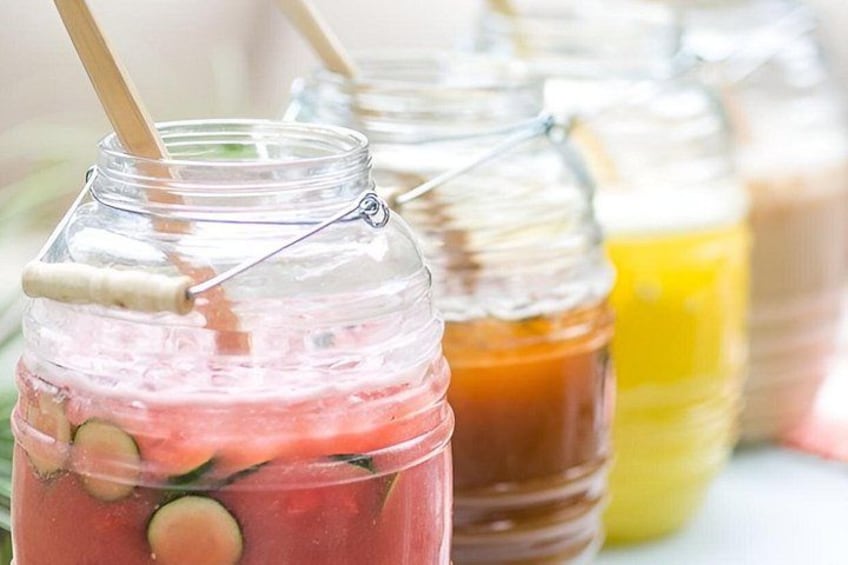 A jar with a straw, containing a pink beverage with cucumber slices. 3