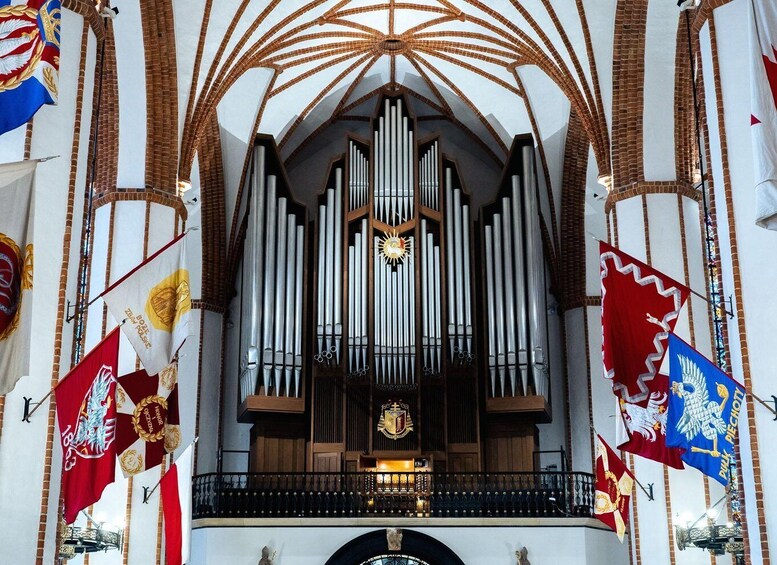A church interior with a large pipe organ, banners, and a vaulted ceiling. 3